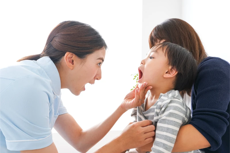 峰歯科・矯正歯科クリニックで歯並びを確認するスタッフとお子様